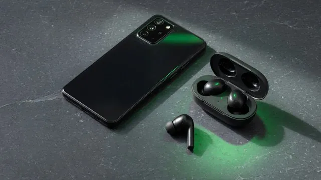 Phone and wireless earbuds on a dark desk under soft green light